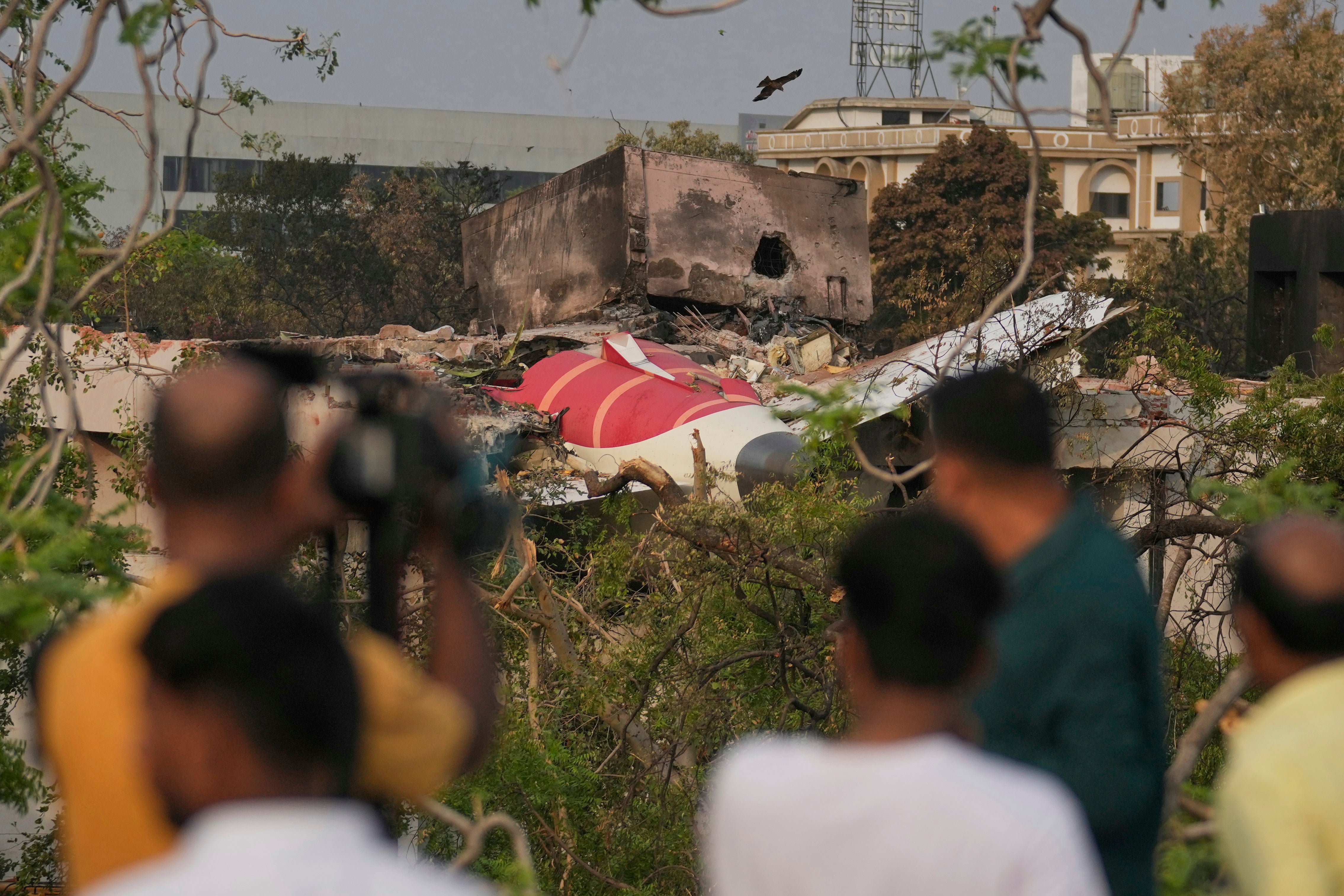Onlookers watch wreckage from Thursday's Air India plane crash lying atop a building in Ahmedabad, India, Saturday