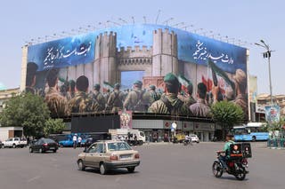 Iranians drive past an anti-Israel poster in Tehran's Enghlab Square on Saturday