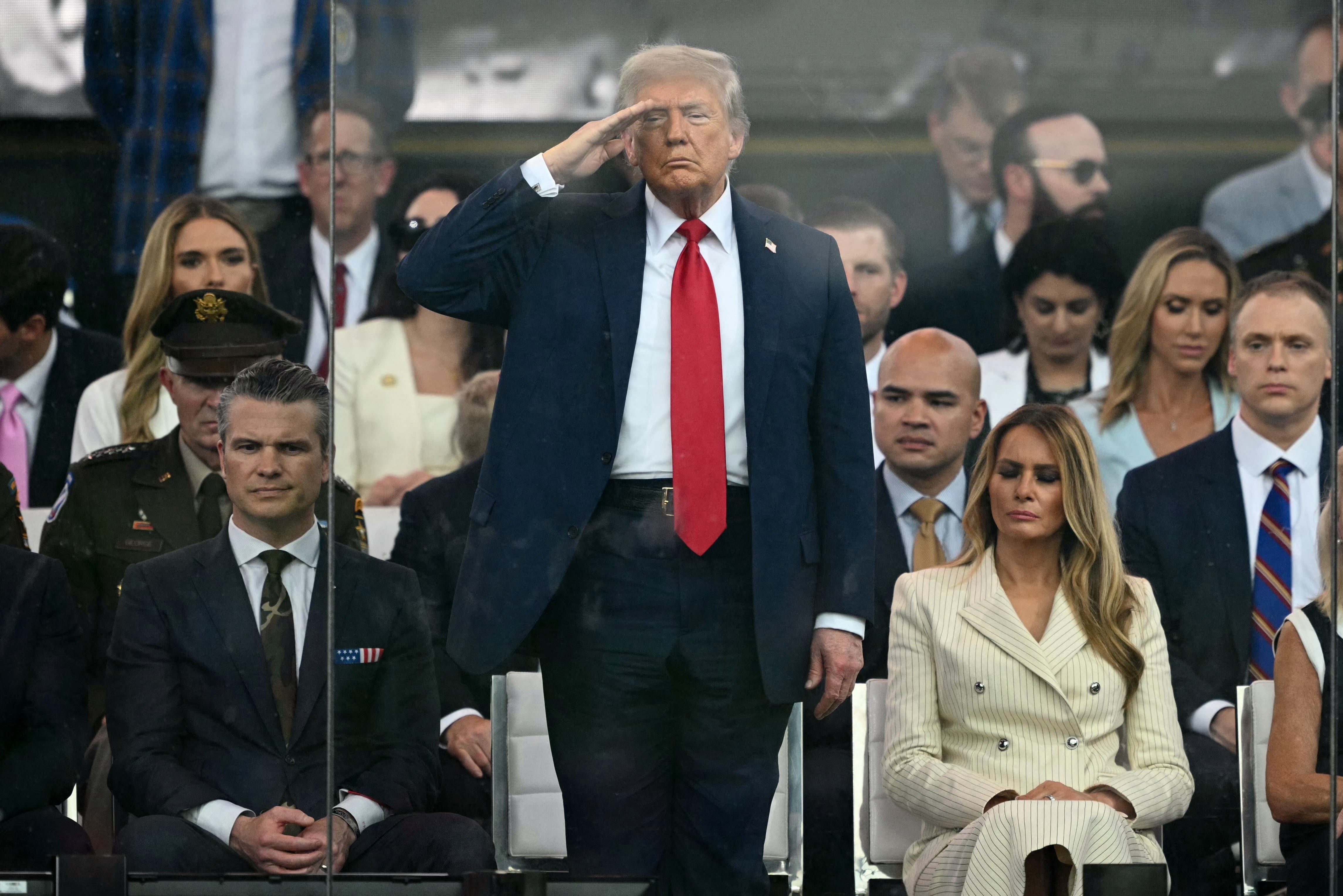 Trump stood to greet the troops as he sat next to the Minister of Defense of Pete Hegseth and the first lady.