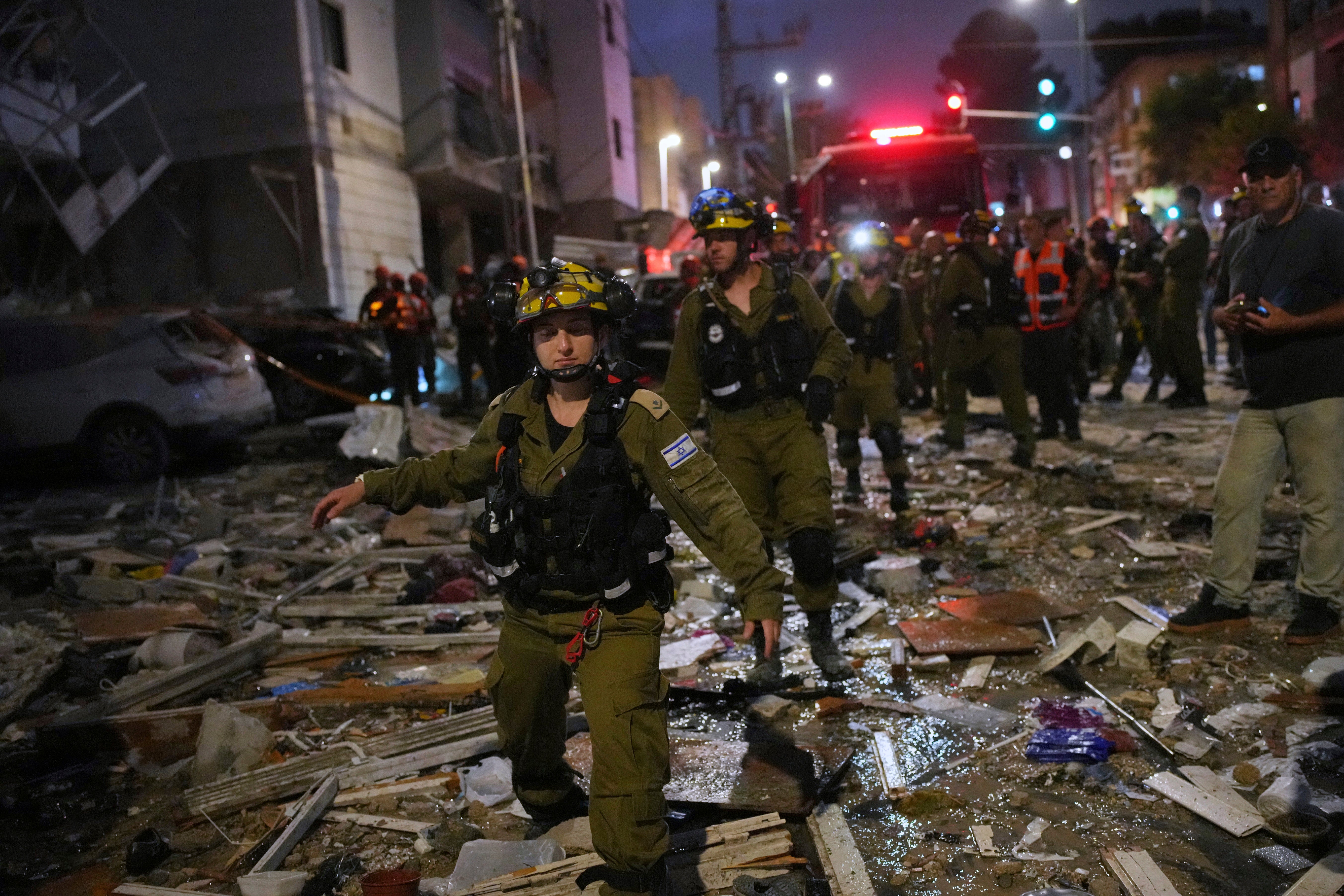 Israeli security forces inspect destroyed buildings that were hit by a missile fired from Iran, near Tel Aviv, Israel, Sunday, June 15, 2025