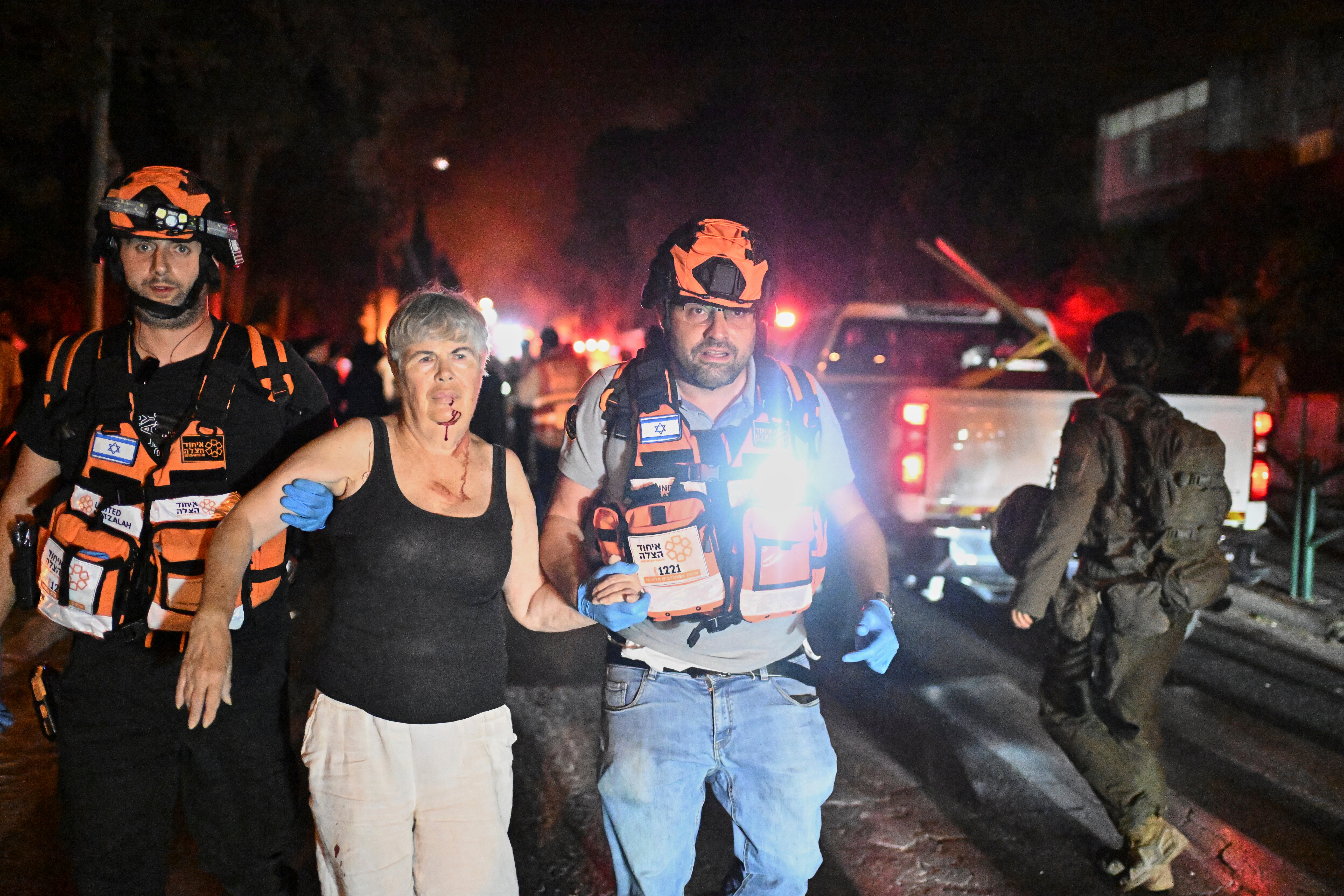 Israeli rescue team takes out an injured woman from a site killed by a missile in Haifa