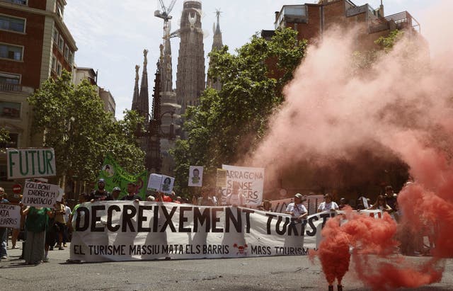<p>Demonstrators hold a banner which reads "Decrease tourism now" and "Tourism kills the neighborhoods" during a protest against mass tourism in Barcelona</p>