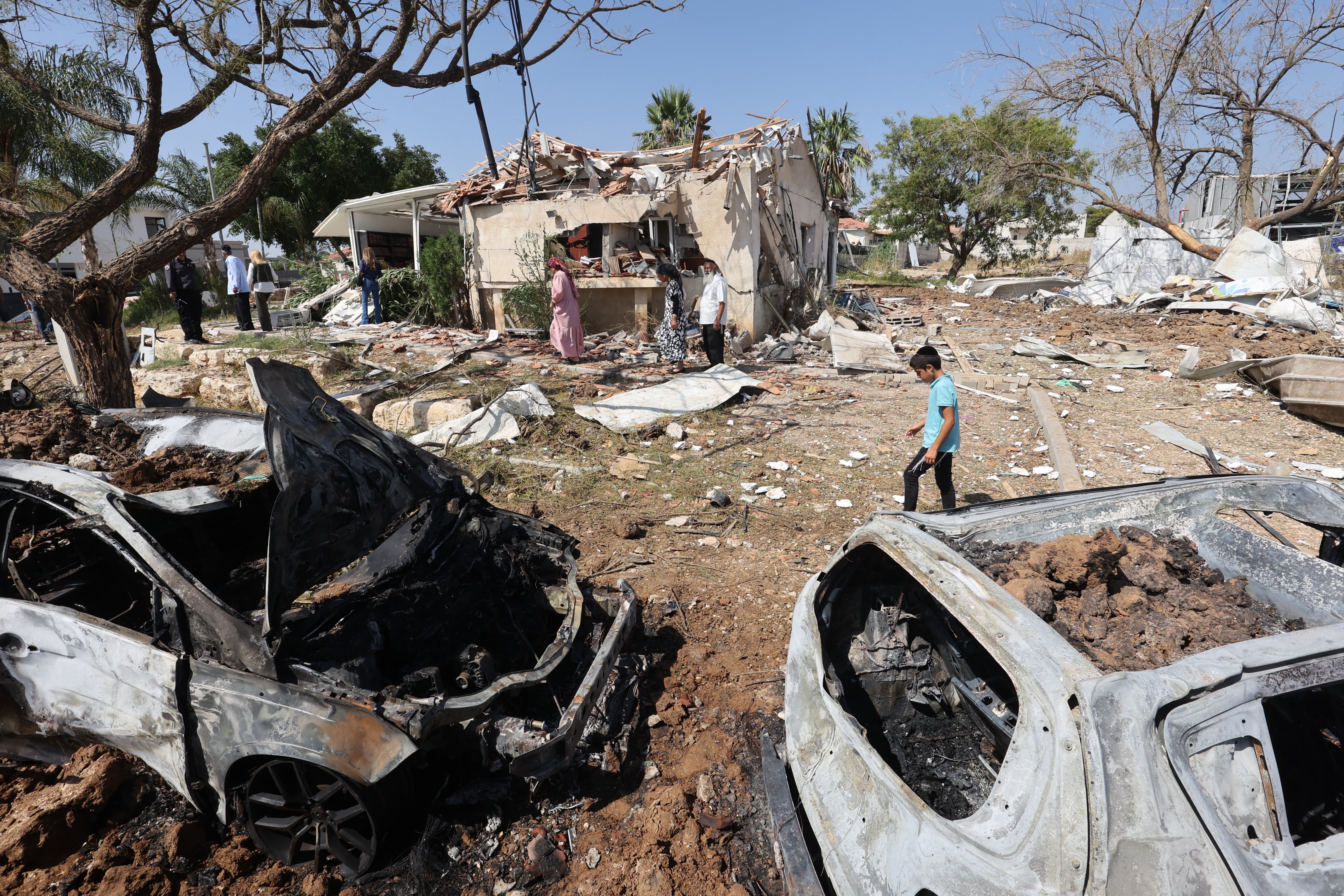 A boy walks next to the damage and debris at the site of an Iranian missile strike in Moshav Zavdiel,