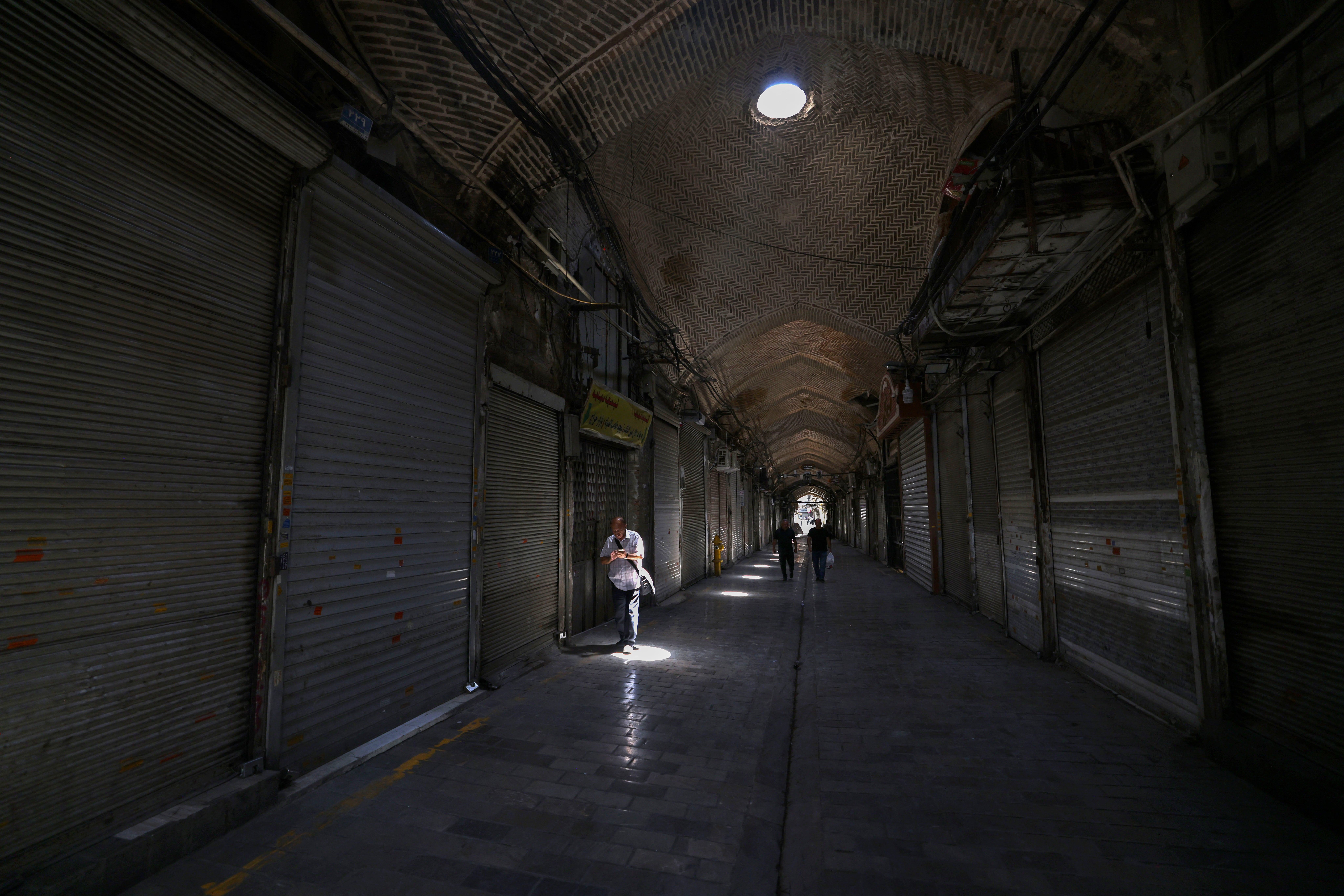 People walk past closed shops in Tehran's Grand Bazaar