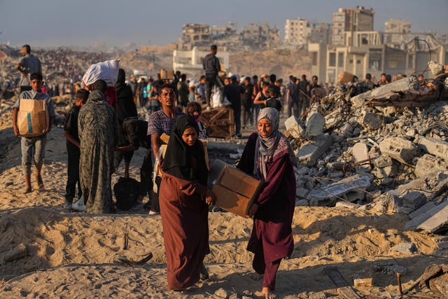 <p>Palestinians carry sacks and boxes of aid from a World Food Programme convoy heading to Gaza City on 16 June 2025</p>