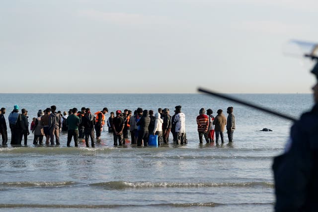 People thought to be migrants wade through the sea to board a small boat leaving the beach at Gravelines, France, in an attempt to reach the UK by crossing the English Channel (Gareth Fuller/PA)
