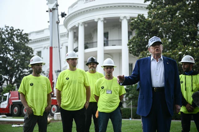 <p>US President Donald Trump speaks to the press as workers install a large flag pole on the South Lawn of the White House </p>