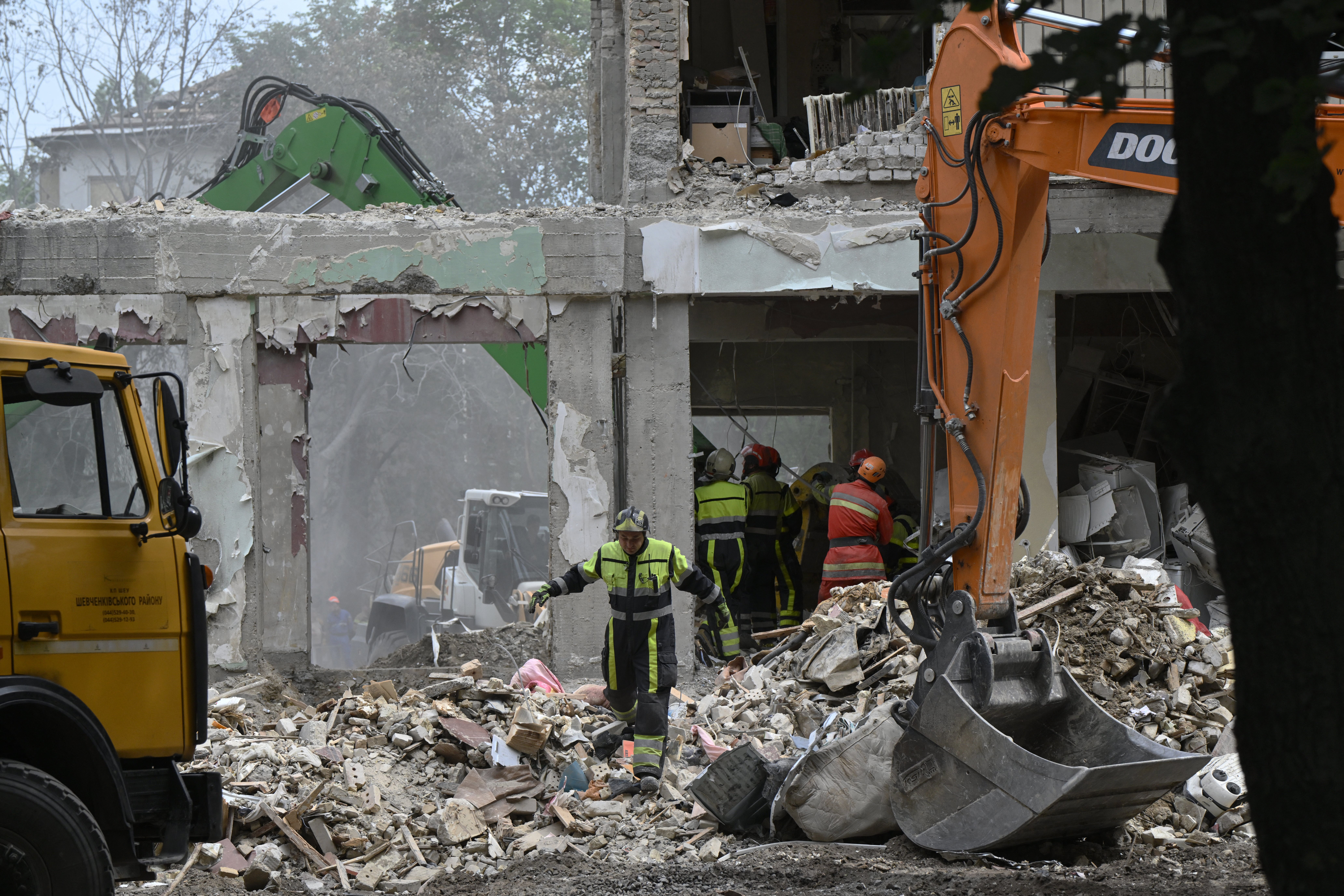 Ukrainian rescuers clear debris as they continue a search operation at the site of a residential building, heavily damaged following a Russian missile strike the previous day, in Kyiv
