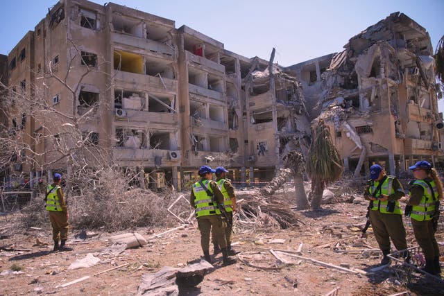 <p>Israeli security forces stand next to a destroyed building that was hit by a missile fired from Iran, in Holon, near Tel Aviv</p>