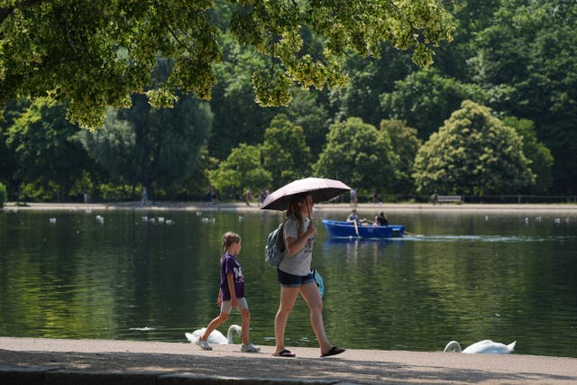 A person shields from the sun under an umbrella in Hyde Park, London (Yui Mok/PA)