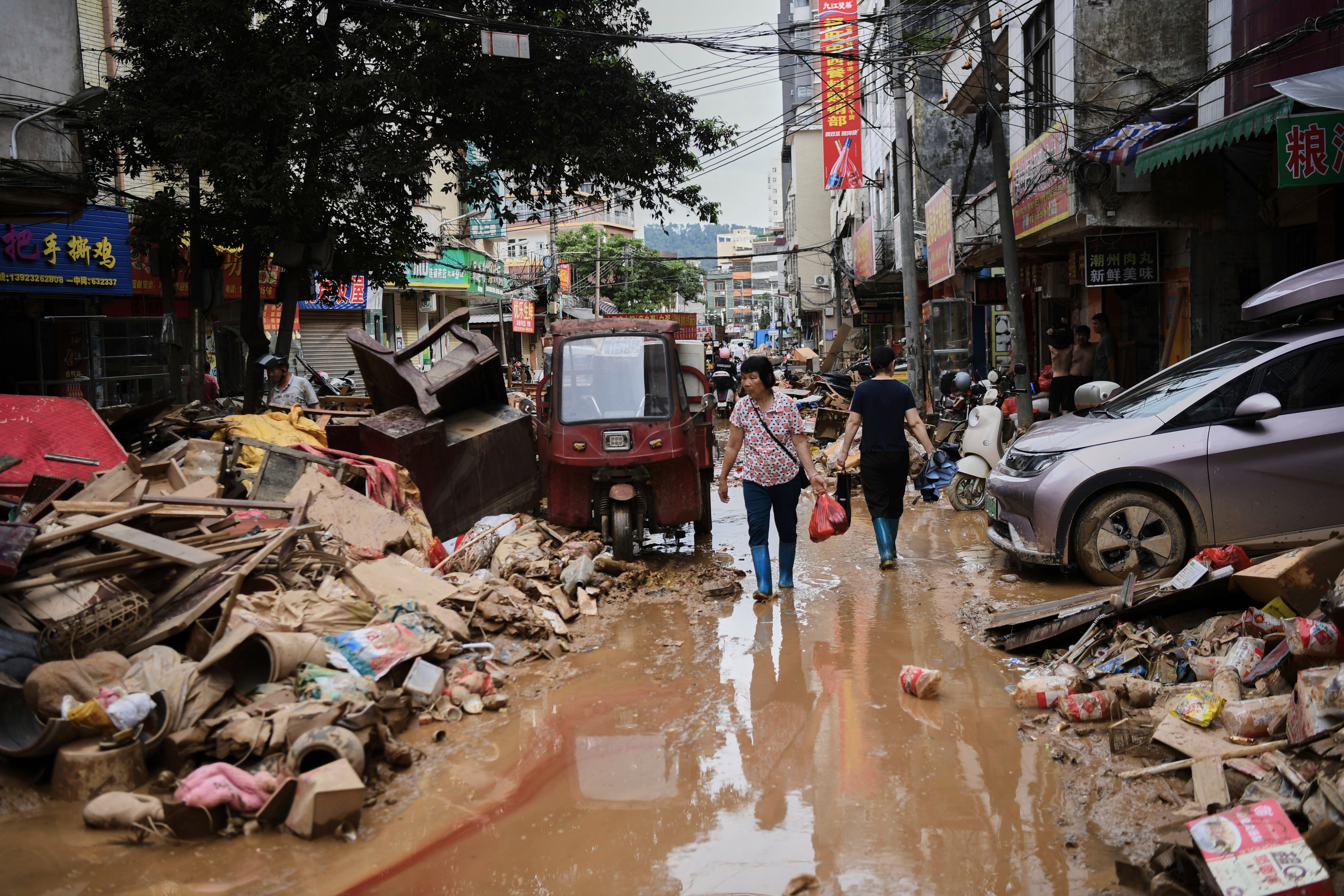 Tropical storm slams into parts of southern China already reeling from deadly flooding Residents wade through debris along a flood-hit street after waters from a river overwhelmed towns following days of heavy rain in Huaiji county of south China's Guangdong province