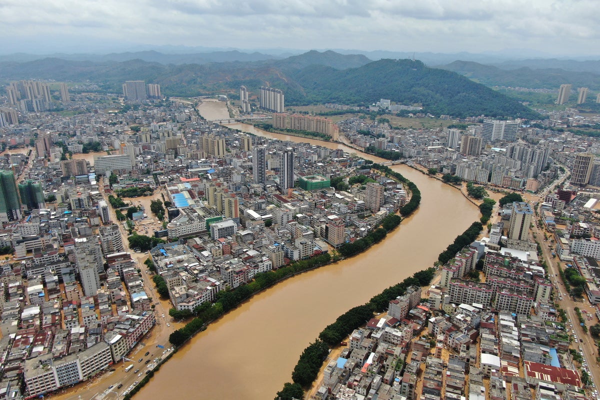 A river overflows in southern China, stranding people and turning streets into canals