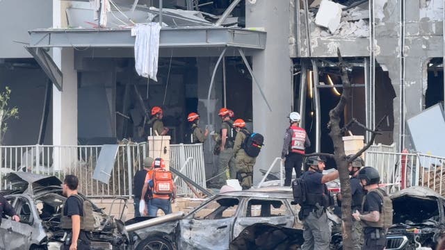 Emergency services officials inspect damage to buildings hit following a missile strike from Iran