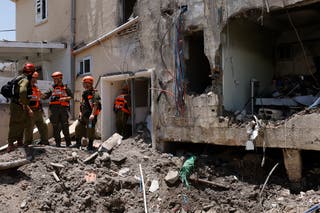 Israeli soldiers and first responders check the damage caused to a building from an Iranian strike in Beit She'an on June 21