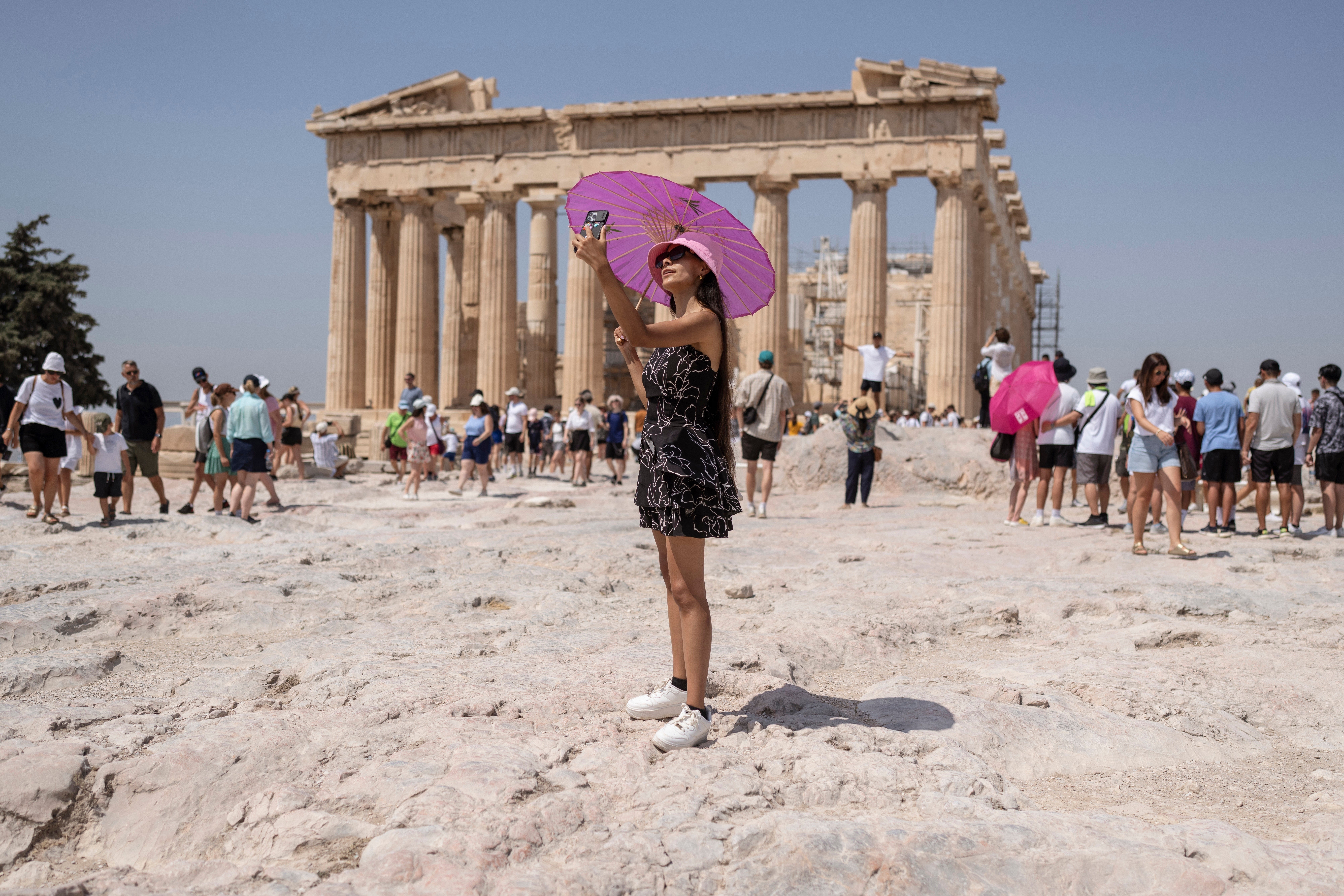 A woman takes a selfie in front of Parthenon temple atop of the ancient Acropolis hill during a heat wave in Athens, Greece, July 21, 2023. (AP Photo/Petros Giannakouris, File)