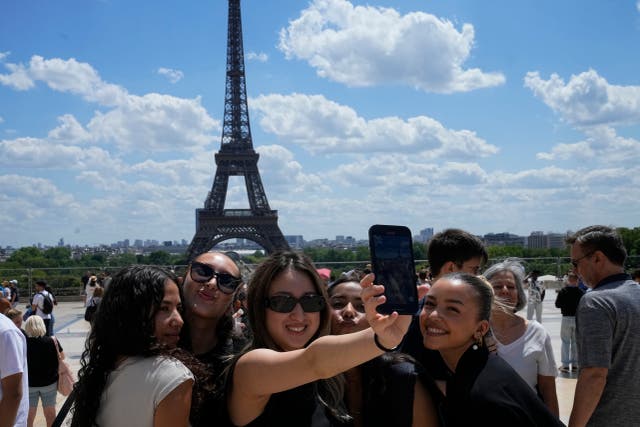 <p>Tourists pose for a selfie with the Eiffel Tower in background</p>
