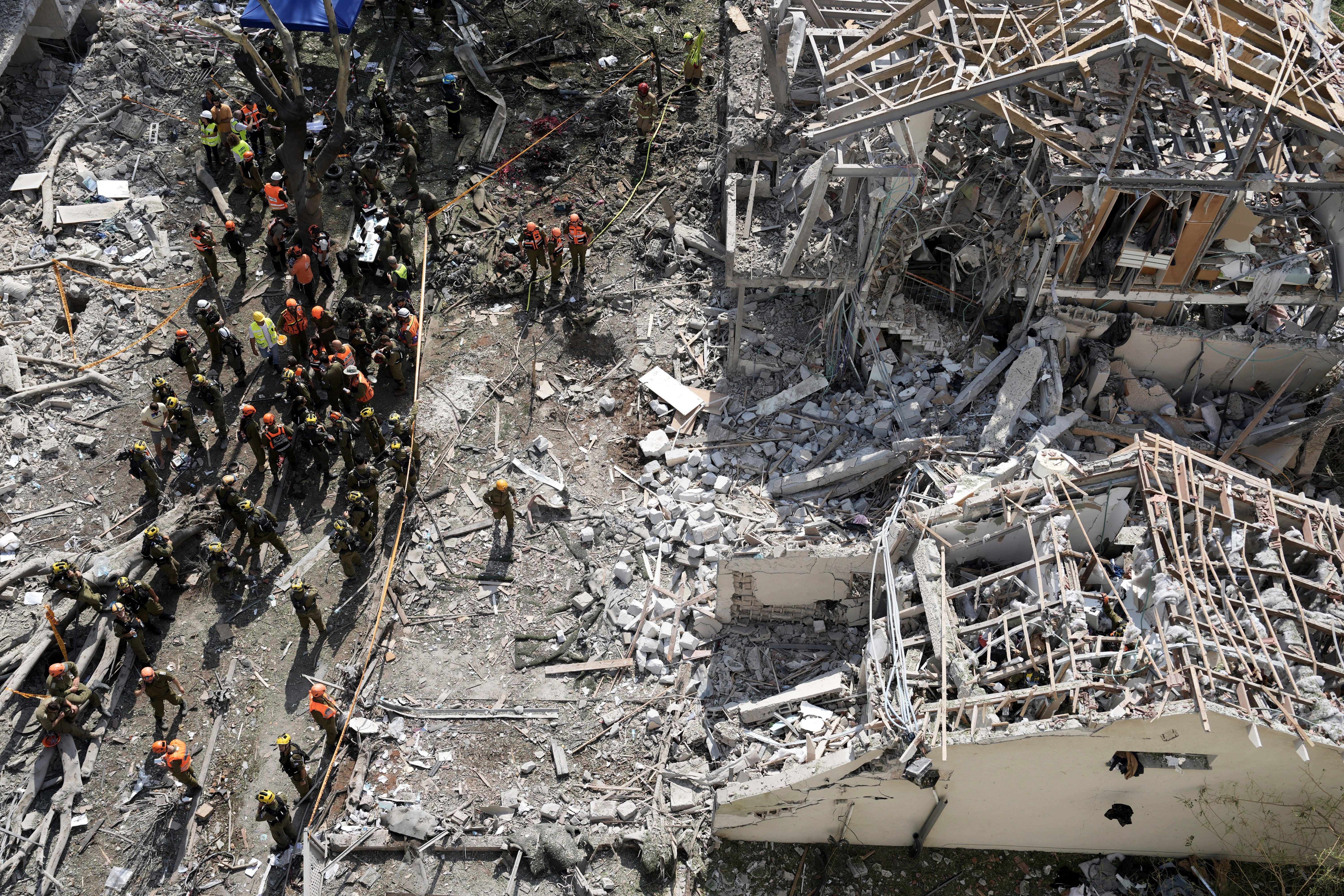Firefighters, rescue workers and military gather at the site of a direct missile strike launched from Iran in Tel Aviv on Sunday