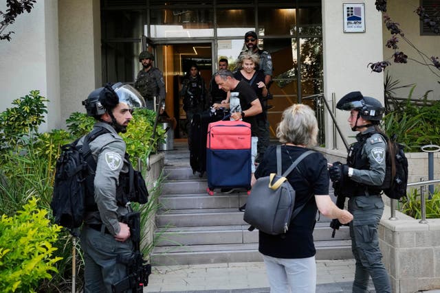 Israeli border police officers help residents evacuate a building damaged in an Iranian missile strike in Tel Aviv, Israel (AP Photo/Bernat Armangue)