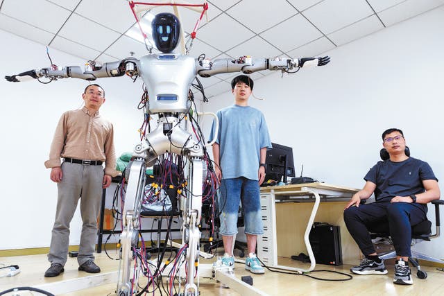 <p>Liu Lizheng (left), head of humanoid robot projects at Fudan University, and his colleagues pose with the Guanghua No 1 humanoid robot on 14 May </p>
