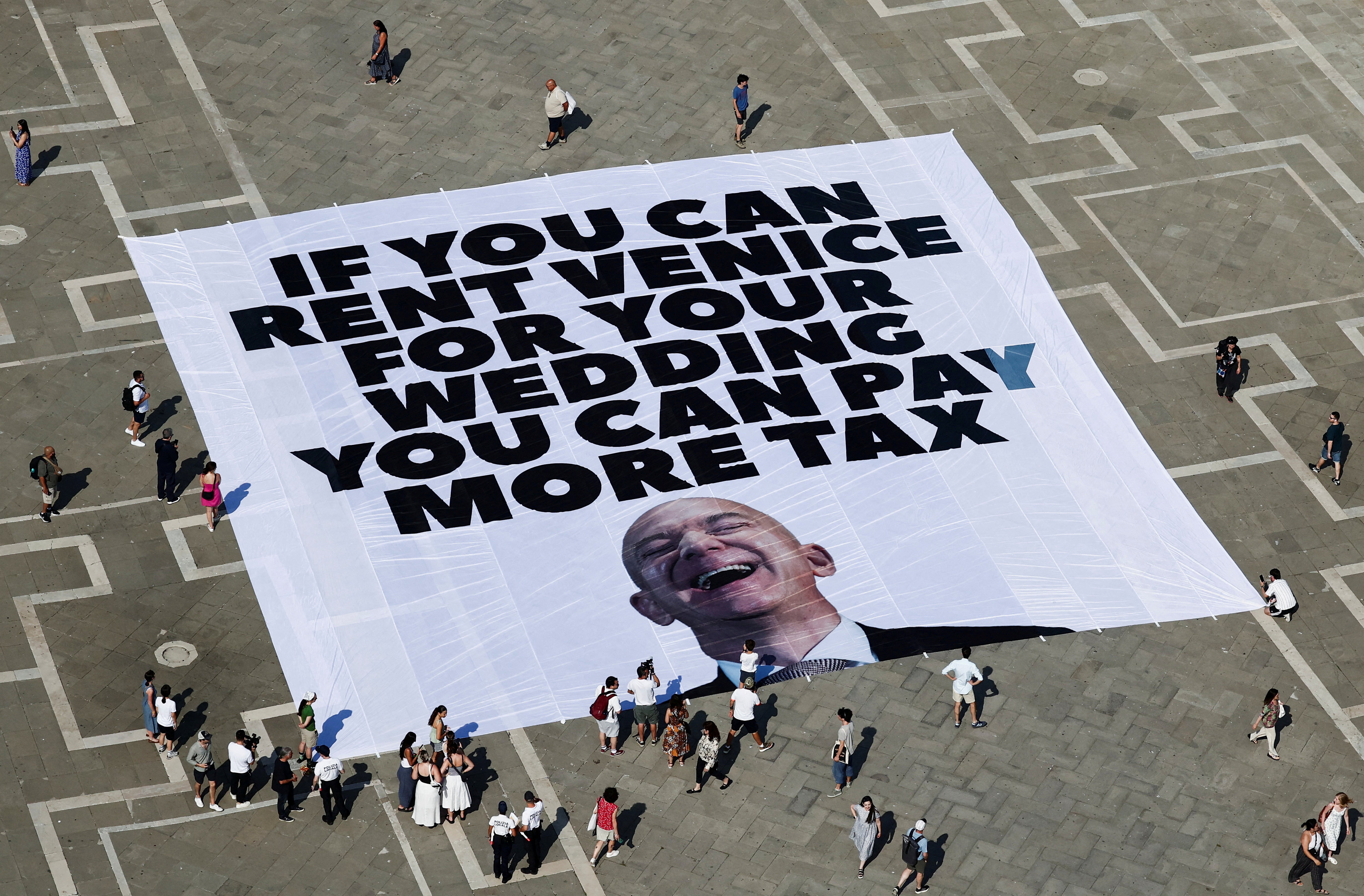 A large banner against Amazon founder Jeff Bezos lies on the ground, placed by Greenpeace Italy activists