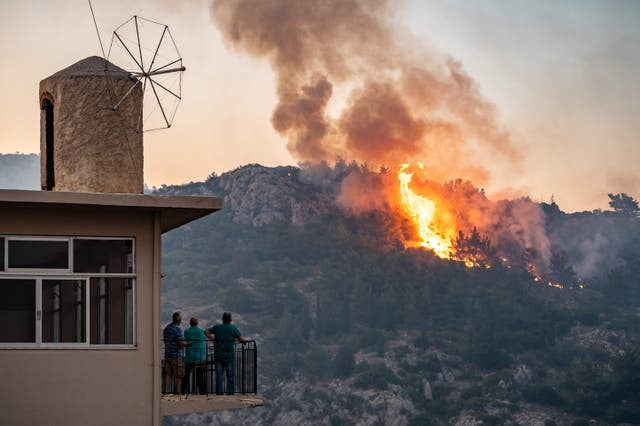 <p>People watch as a wildfire burns forest land on Chios Island</p>