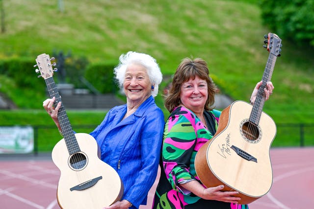 Lady Mary Peters and Julie Hastings show off the guitars donated by Sir Van Morrison and Ed Sheeran (MT Hurson/PA)