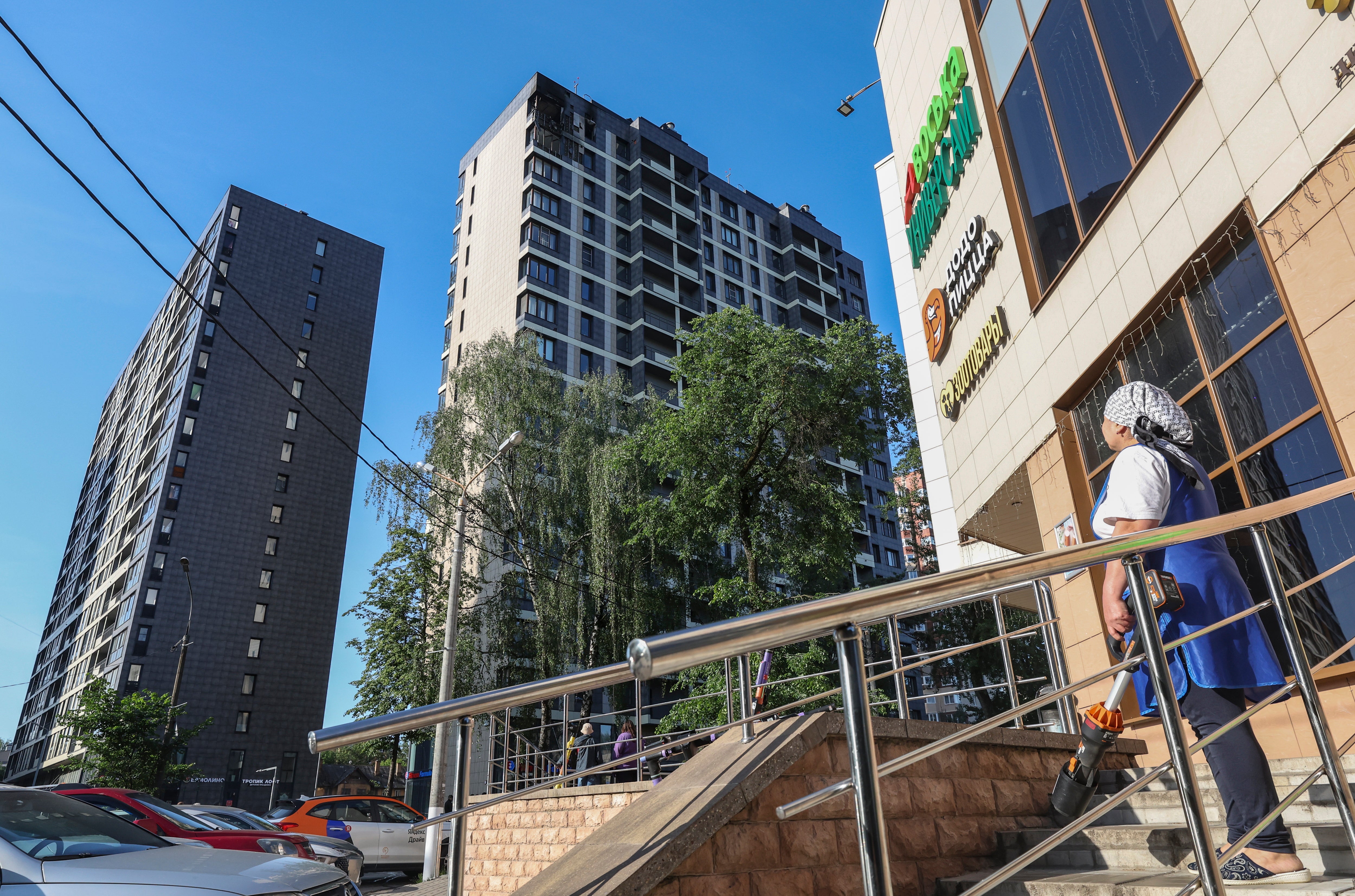 A woman looks at a damaged apartment building following a Ukrainian drone attack in Krasnogorsk