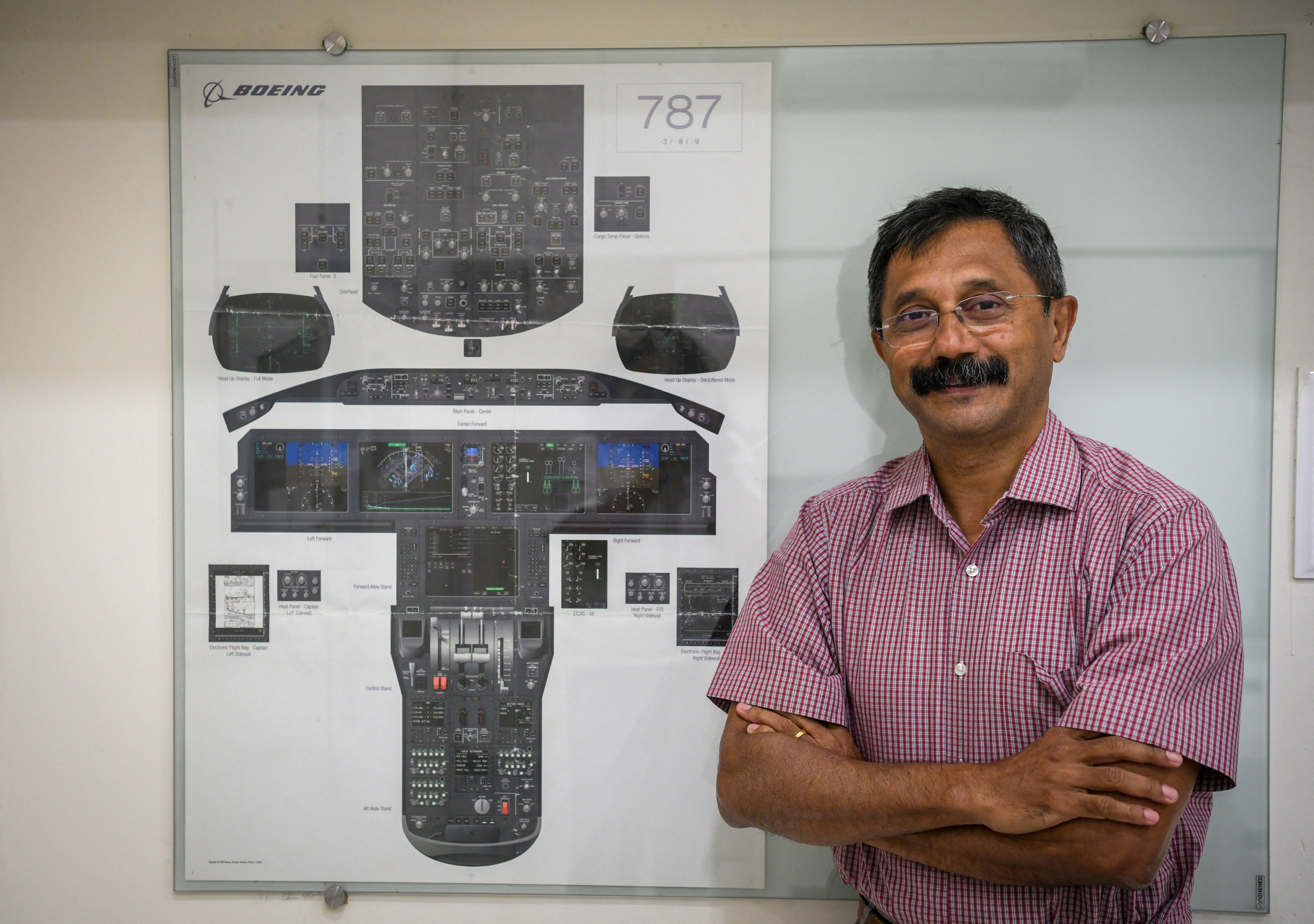 Retired Indian Air Force (IAF) wing commander K. Dinesh poses for a picture next to the layout of Boeing 787 cockpit in the demo room of Cockpit Vista in Bengaluru, India June 23, 2025. REUTERS/Meghana Sastry