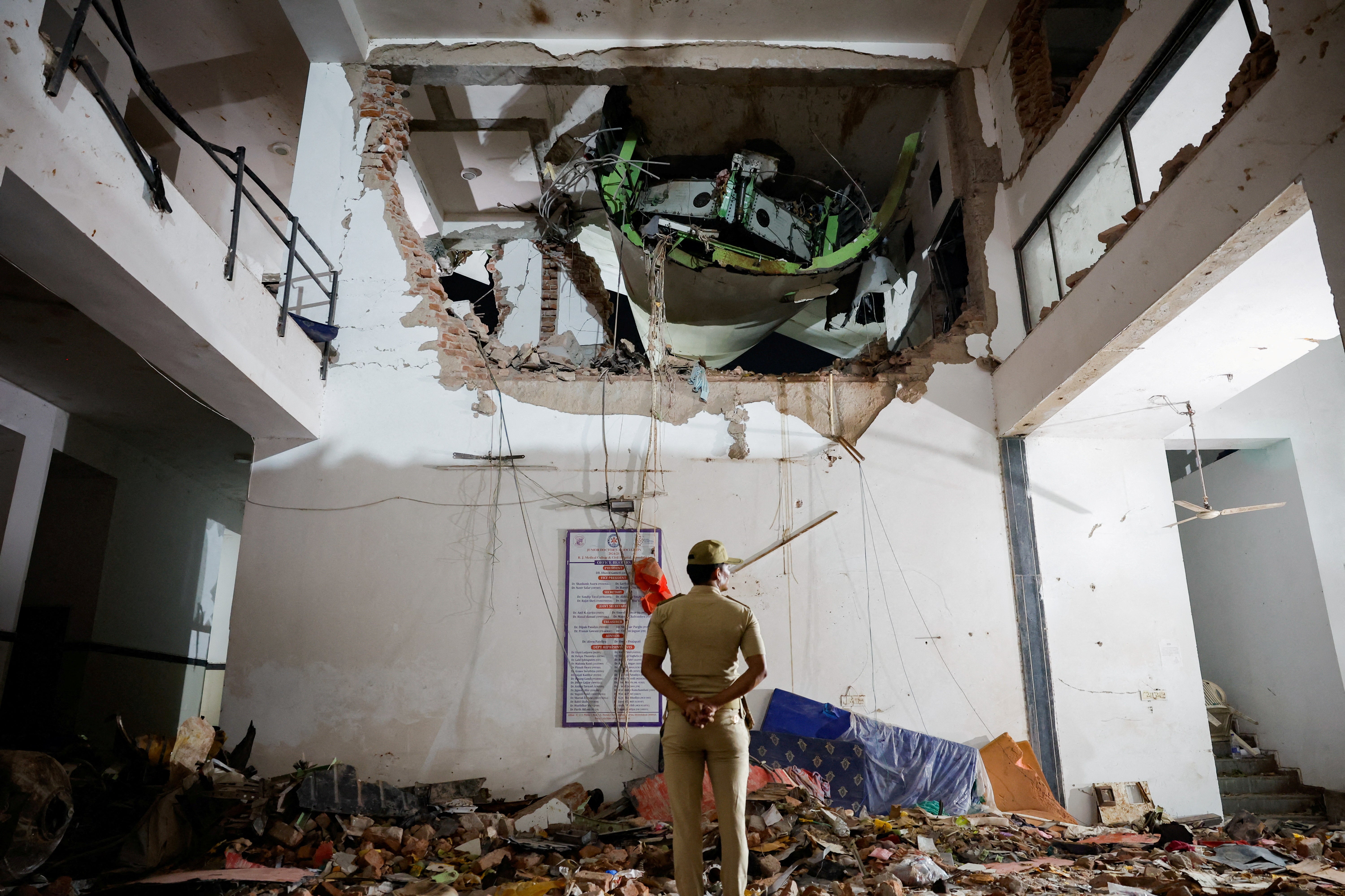 A police officer stands in front of the wreckage of an Air India aircraft, bound for London's Gatwick Airport, which crashed during take-off from an airport in Ahmedabad, India June 12, 2025