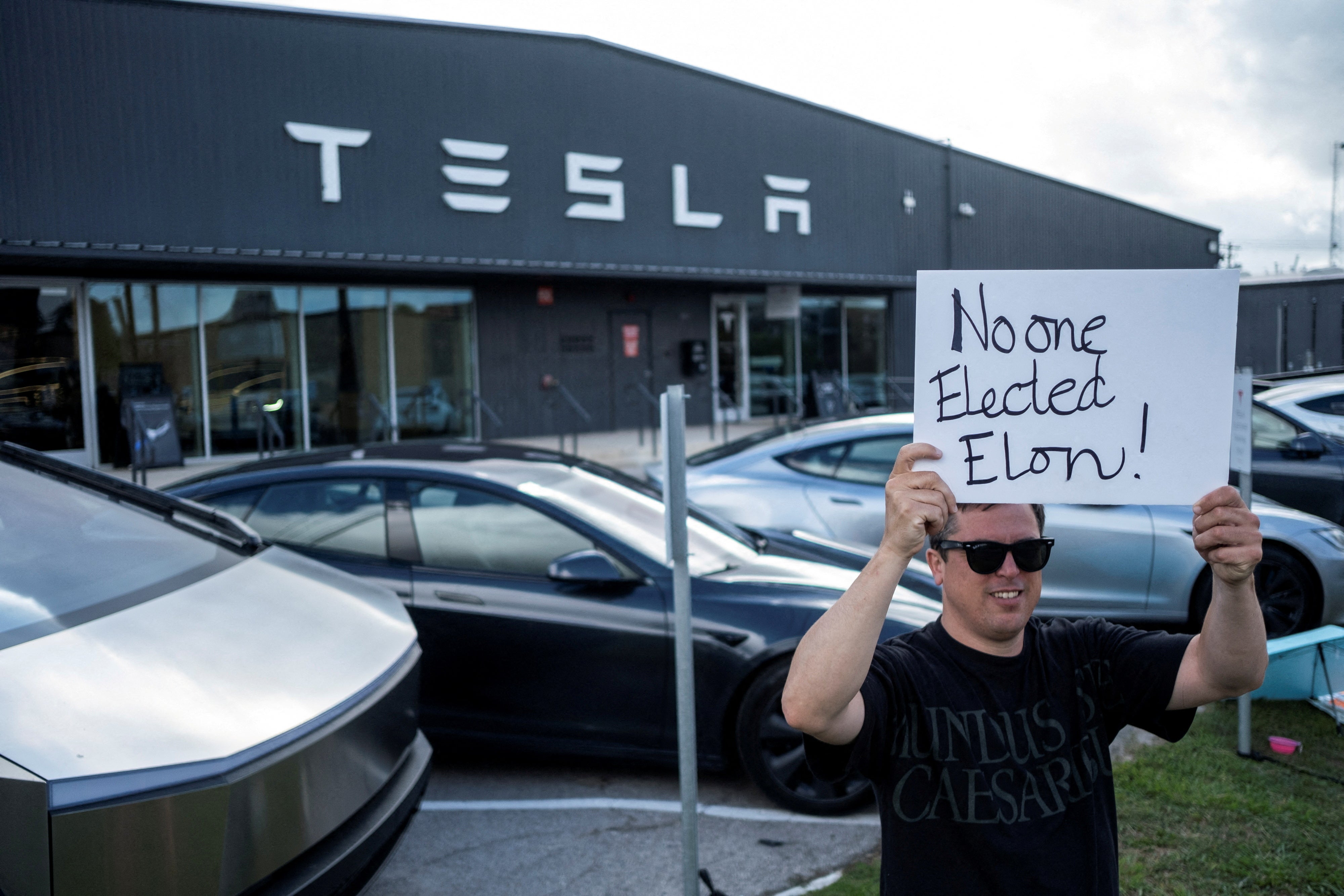 A demonstrator protests against Tesla and its CEO Elon Musk, outside a Tesla service center and gallery in Austin, Texas