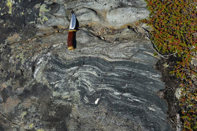 <p>This photo provided by researcher Jonathan O'Neil shows an outcropping of rocks from Canada's Nuvvuagittuq Greenstone Belt dated to about 4.16 billion years old, with a knife to indicate scale. (Jonathan O'Neil via AP)</p>
