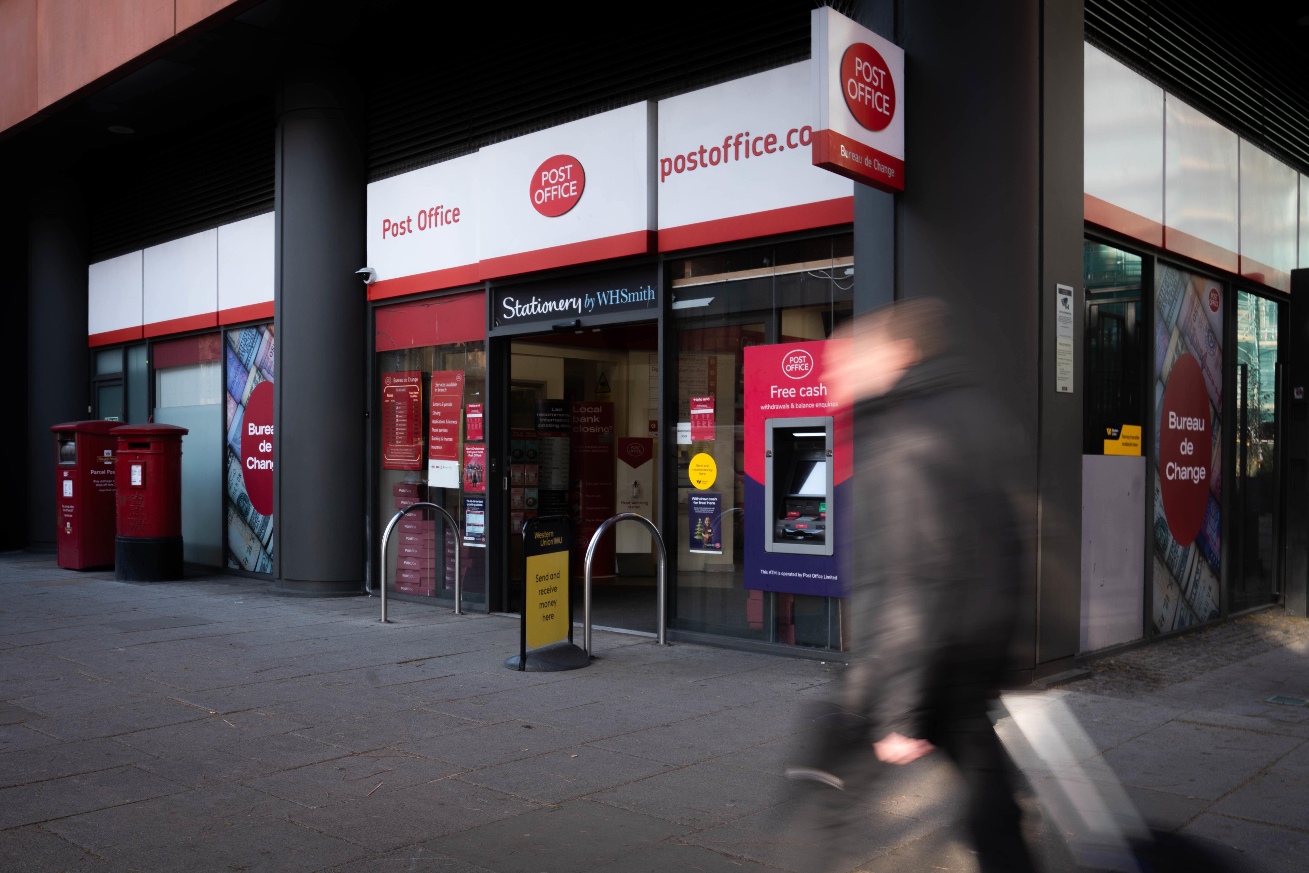 A person walks past a branch of the Post Office in Paddington (PA)