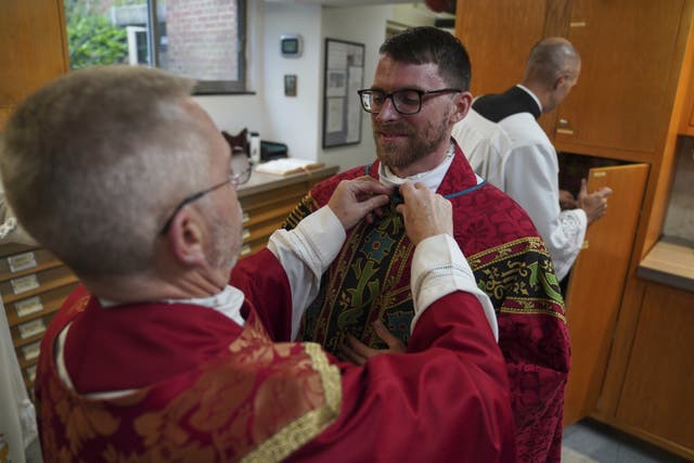 <p>The Rev. Donald J. Planty, Jr., left, assists the Rev. Tim Banach with a microphone before Banach's first Mass at St. Charles Borromeo Catholic Church in Arlington, Va</p>