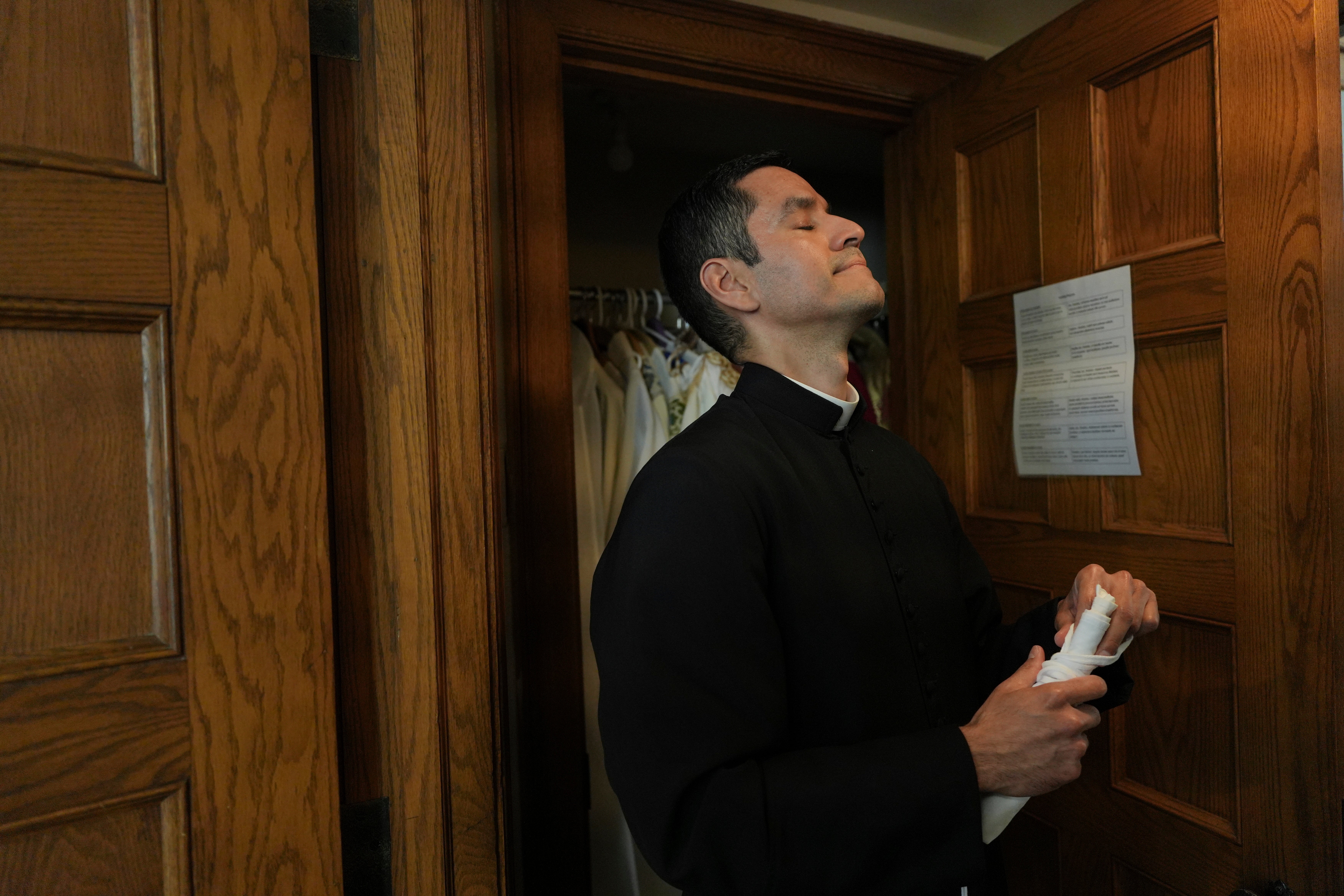 The Rev. Alfredo Tuesta pauses after changing his vestments following a Mass at St. James Catholic Church, Falls Church