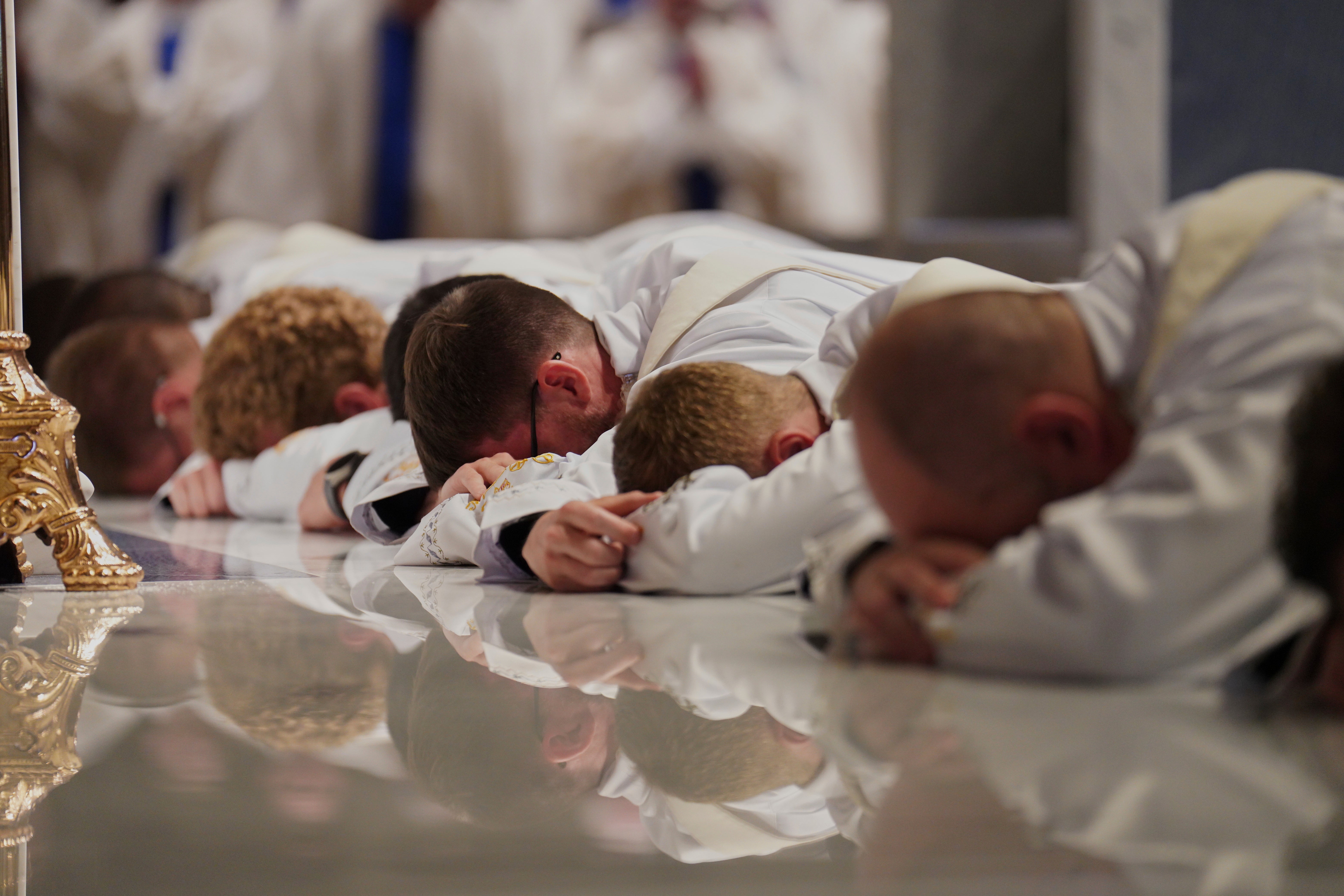 <p>Twelve deacons prostrate in front of the altar at the Cathedral of Saint Thomas More during their ordination Mass in Arlington</p>