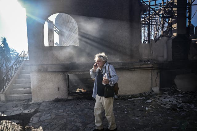 <p>A man talks on his phone as he stands next to a burnt house following a wildfire, in Thymari, southeast of Athens, on June 26, 2025. A forest fire broke out on June 26, 2025 near the seaside towns of Palaia Fokaia and Thymari, 50 km southeast of Athens, leading to evacuations and damaging houses, according to the Greek fire department and public broadcaster Ert. (Photo by Aris MESSINIS / AFP) (Photo by ARIS MESSINIS/AFP via Getty Images)</p>
