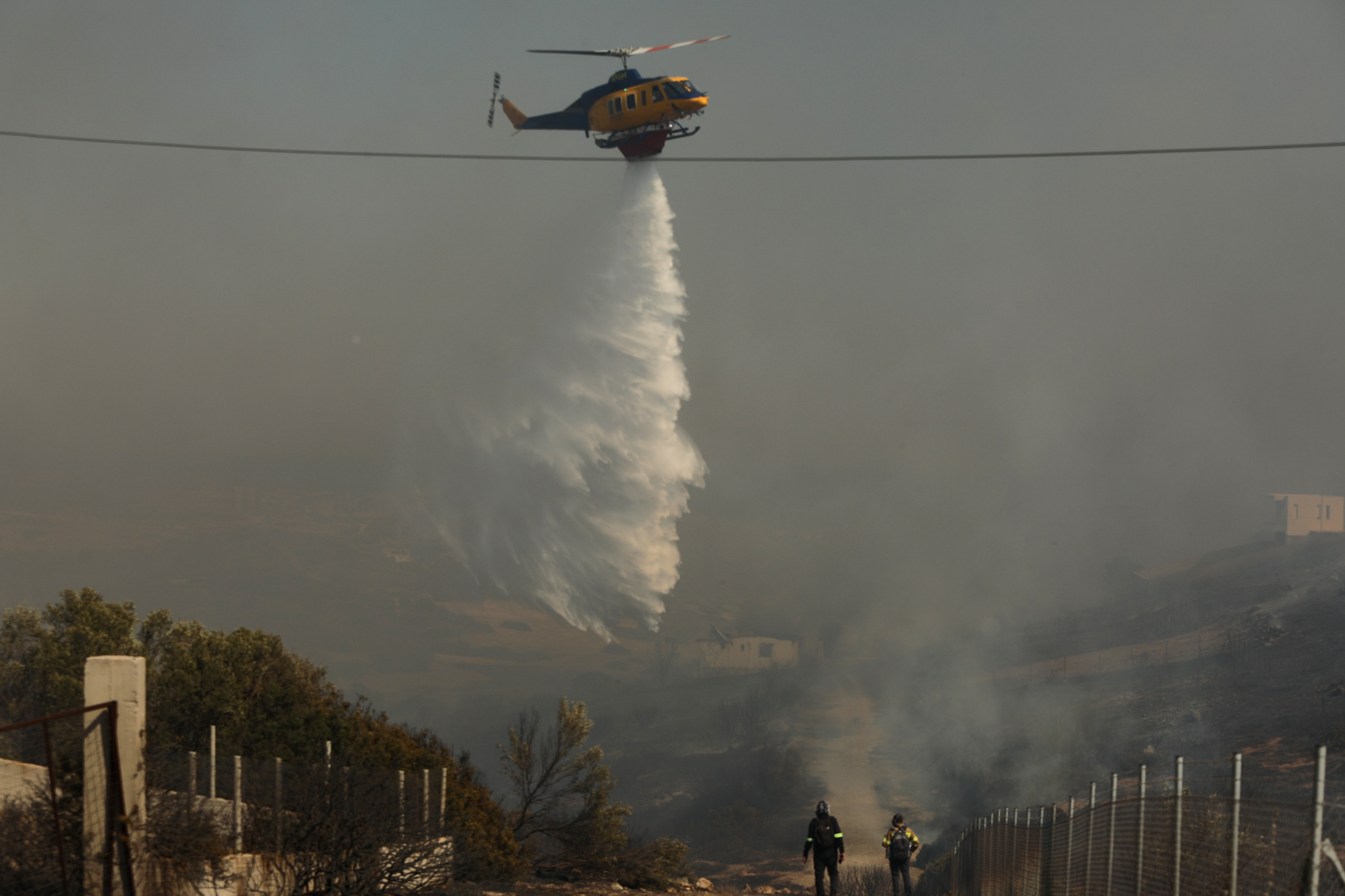 A firefighting helicopter douses a wildfire burning in the coastal region of Palaia Fokaia, some 40km southeast of Athens