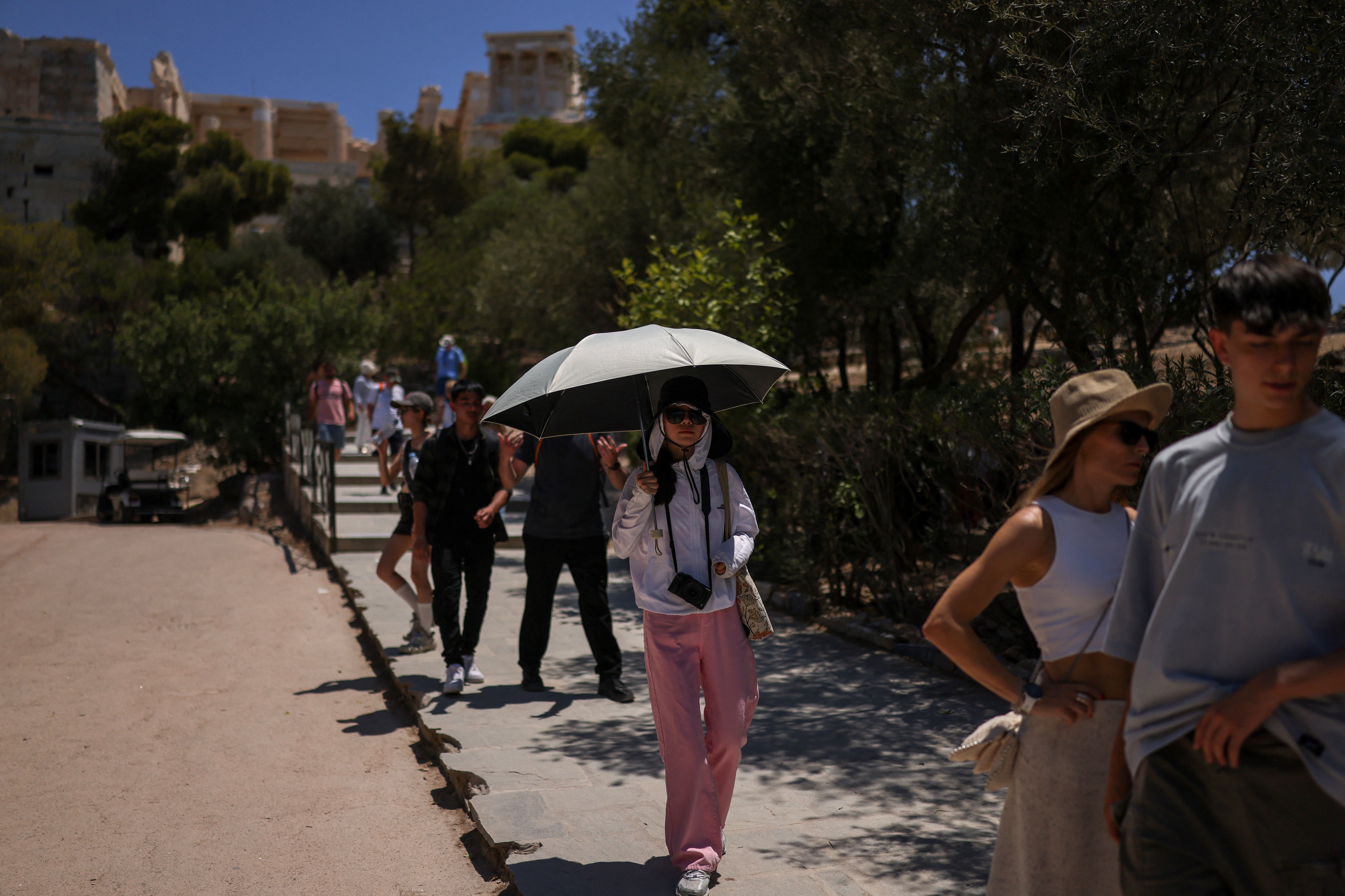 A tourist holds an umbrella to protect from the sun at the Acropolis hill archaeological site, as a heatwave hits Athens