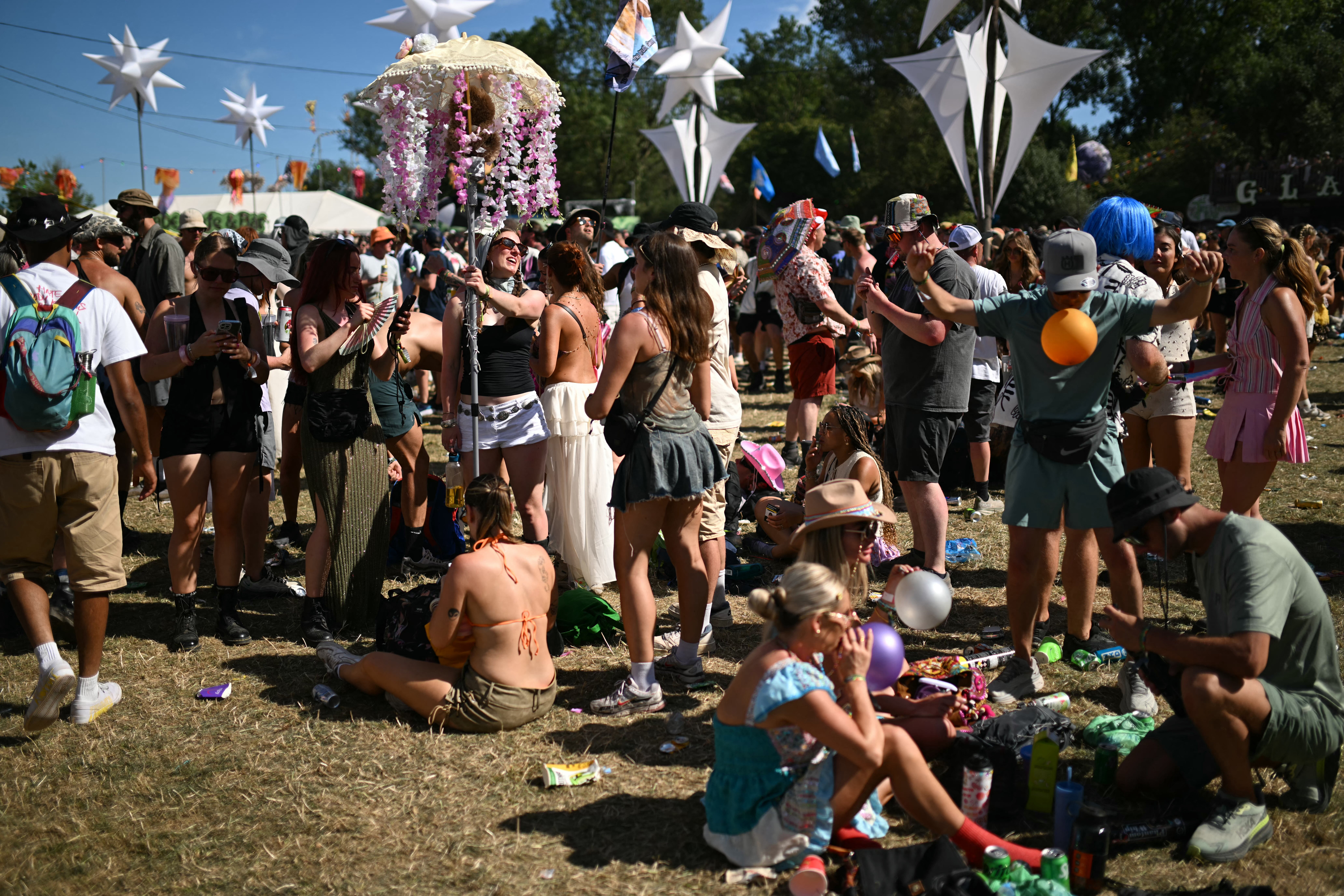 <p>Festivalgoers relax in the sunshine on the third day of the Glastonbury Festival</p>