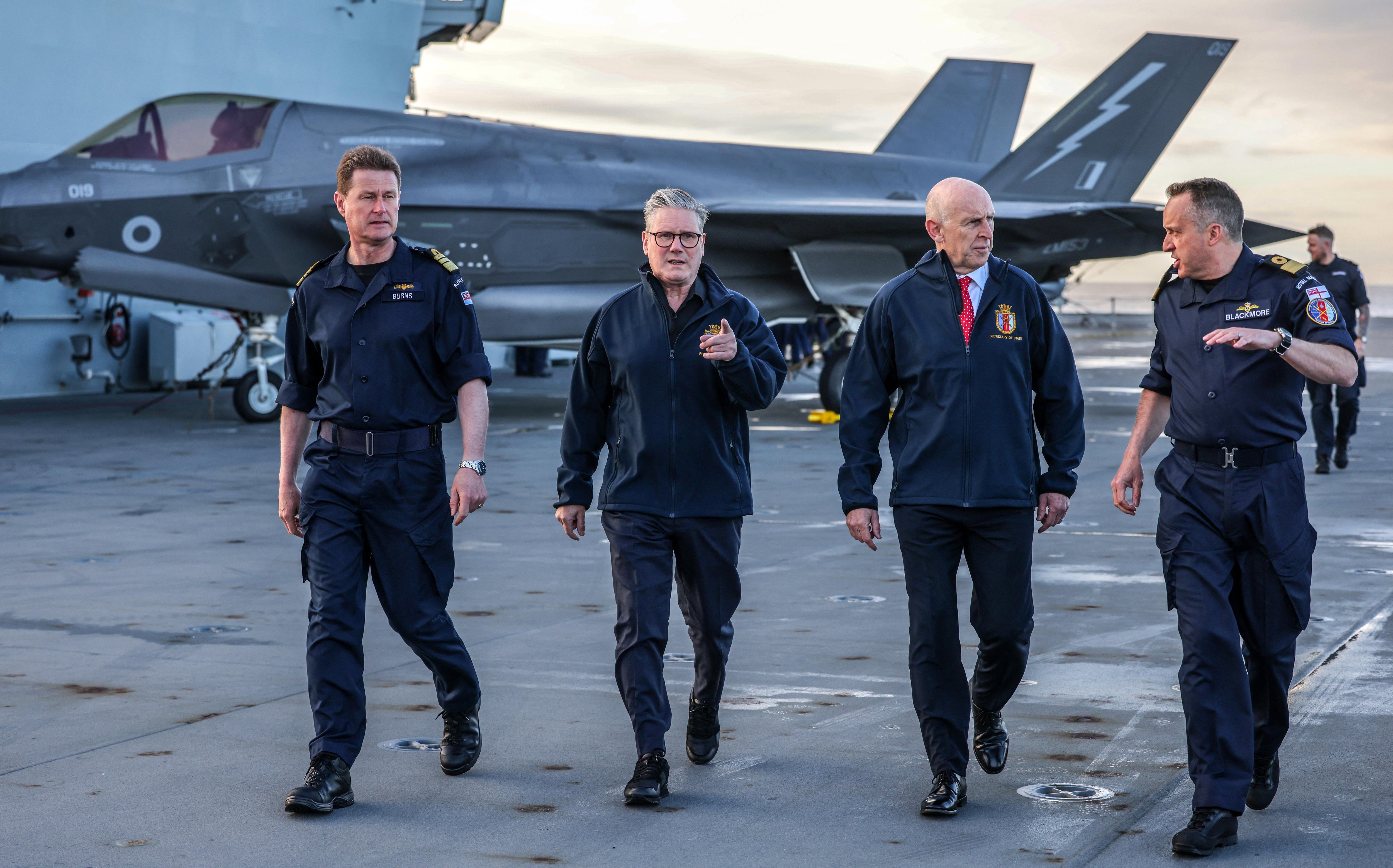 Prime minister Keir Starmer and defence secretary John Healey stand in front of an Royal Air Force F-35B Lightning fighter jet on the flight deck of the British aircraft carrier HMS Prince Of Wales in an undisclosed location