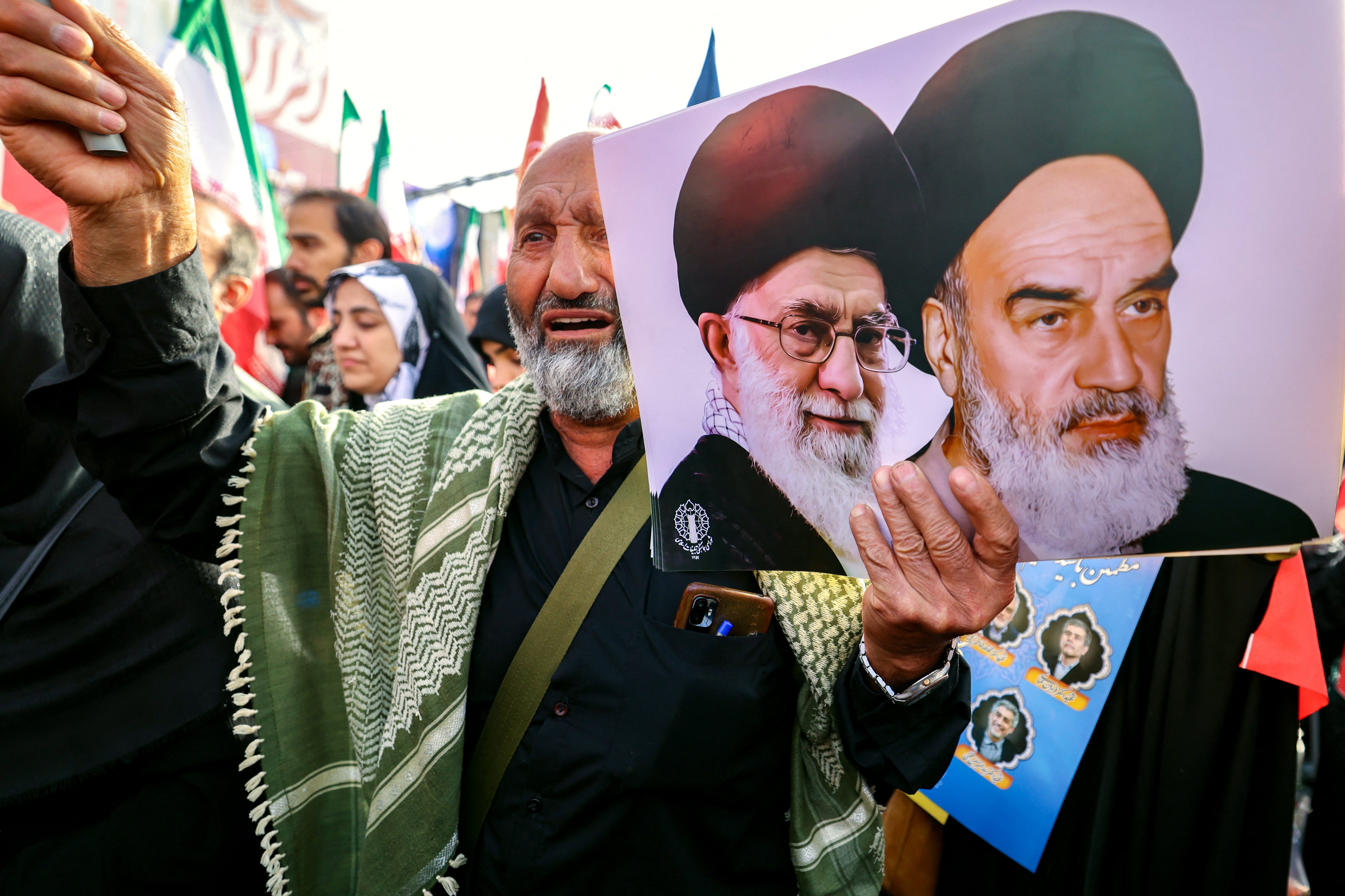 A man holds portraits of Iran's supreme leader Ayatollah Ali Khamenei and his predecessor Ayatollah Ruhollah Khomeini at a state funeral for Iranians killed in Israeli attacks