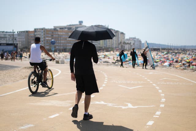 <p>A man uses an umbrella to shield himself from the scorching sun during the first heatwave of the year in Lisbon, on June 29, 2025</p>