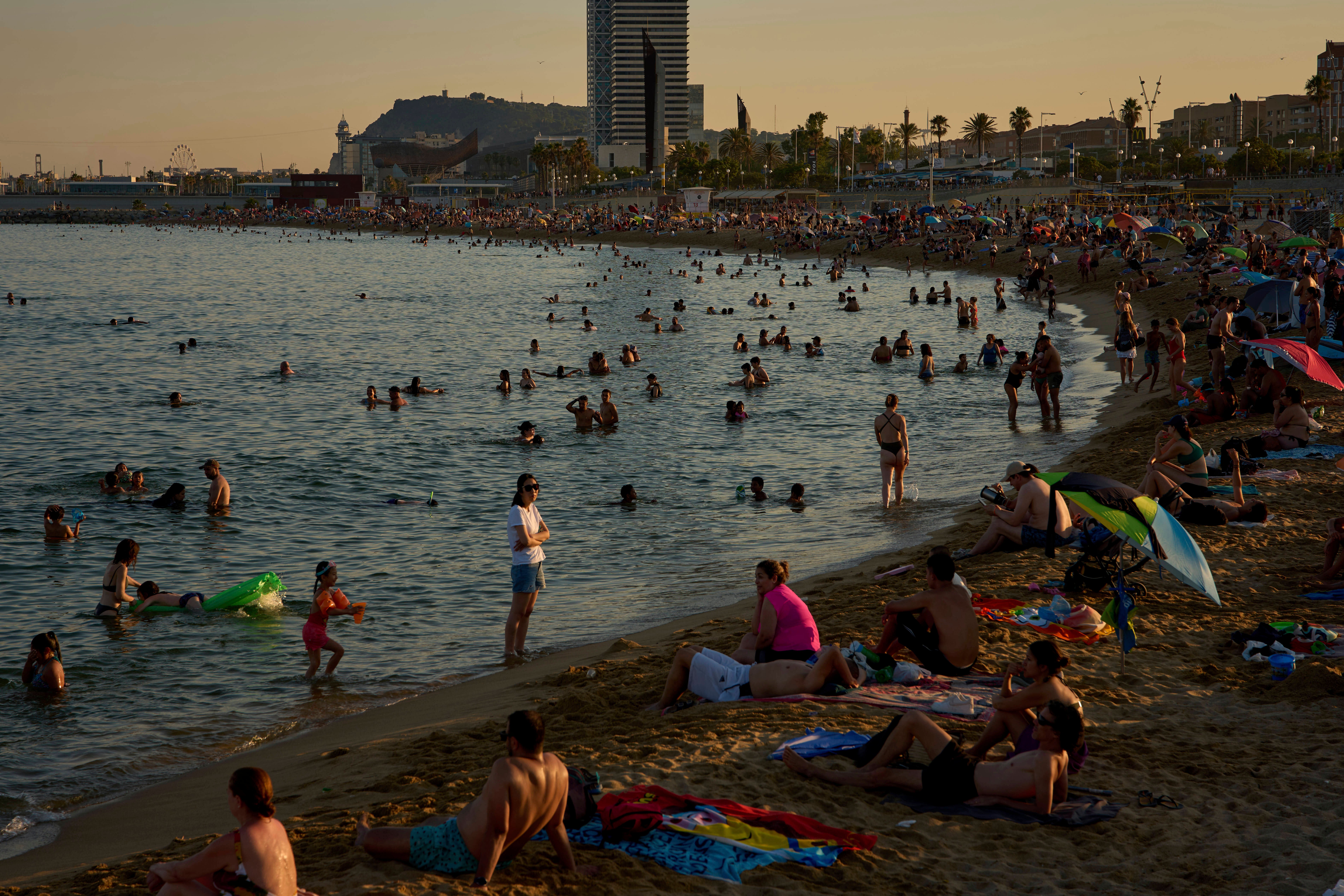 Swimmers cool off in the water at a beach on a hot day in Barcelona