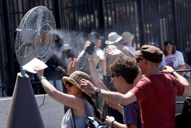 <p>Tourists stand in front of a cooling fan installed outside the Colosseum in Rome on Monday </p>