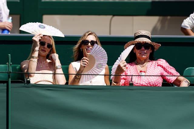Spectators use fans to cool down on day one of the 2025 Wimbledon Championships at the All England Lawn Tennis and Croquet Club (Jordan Pettitt/PA)