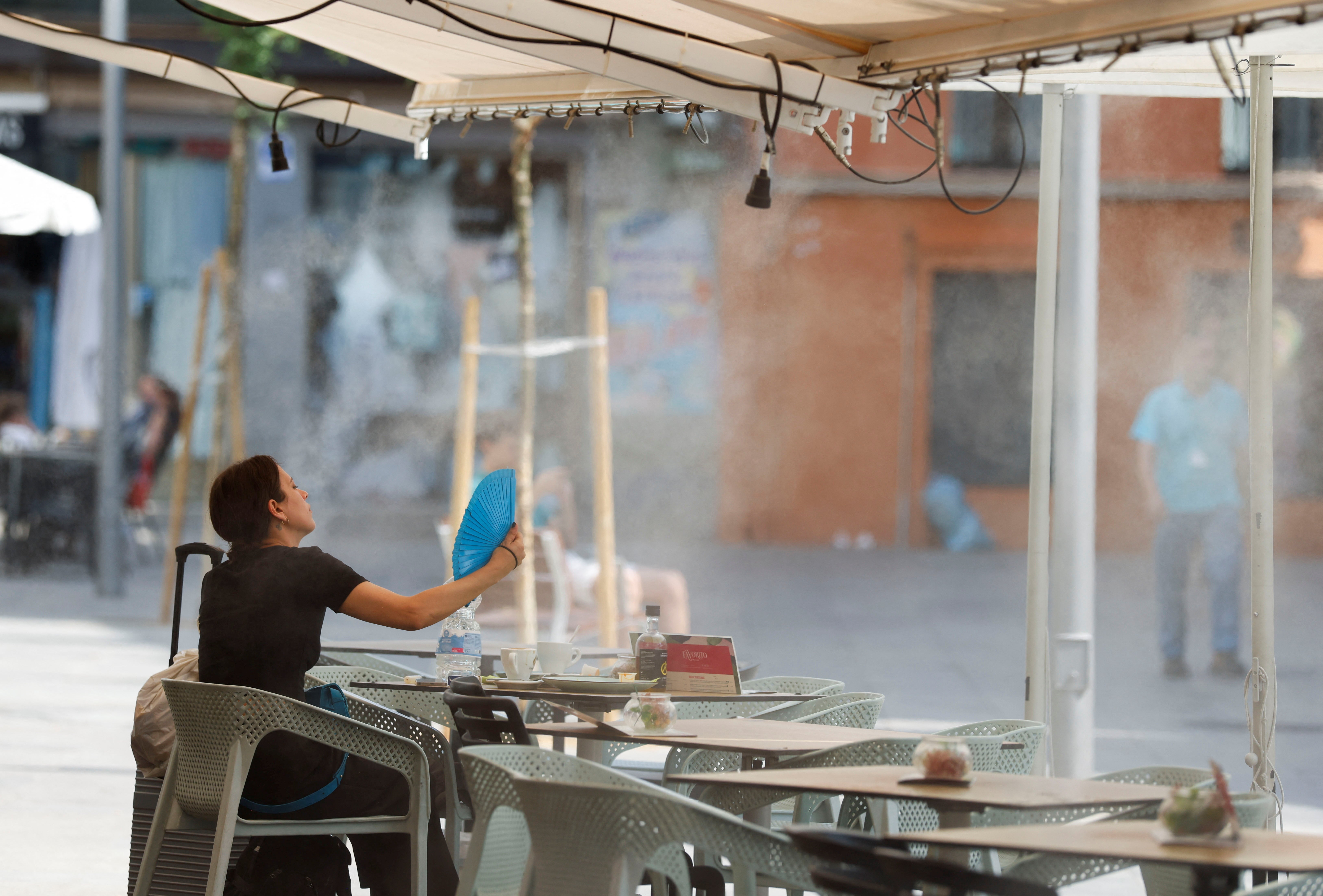A woman uses a hand fan to cool off during the first summer heatwave in Seville