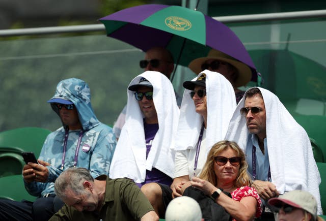 <p>Spectators at Wimbledon use towels for cover amid heatwave conditions </p>