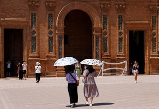 Women use umbrellas to protect themself from the sun during a heatwave in Seville
