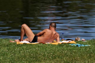 A man rests on the grass on the banks of the river Spree on a hot summer day in Berlin