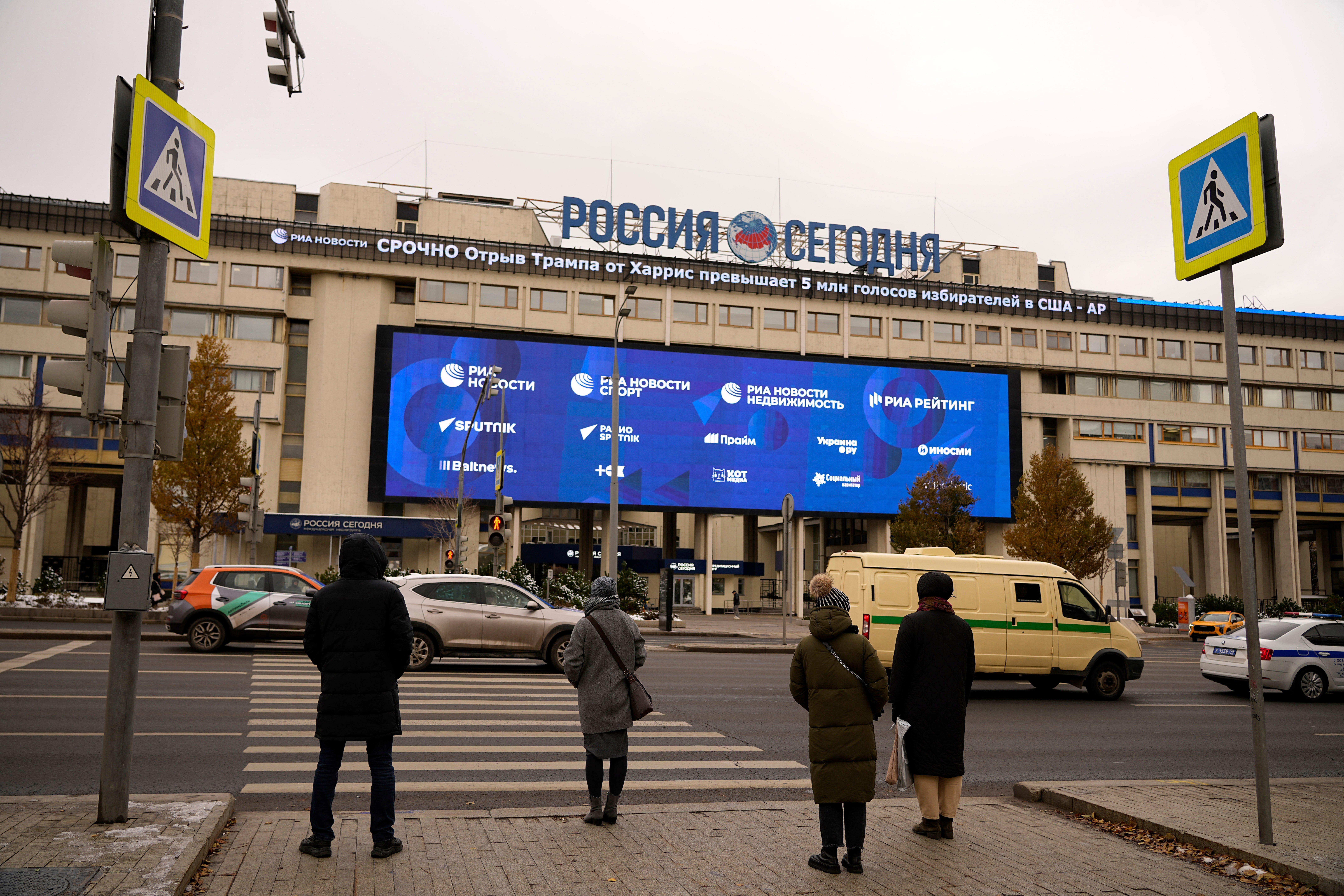 Pedestrians stand at the crossing in front of the Rossiya Segodnya International Media Group building in Moscow